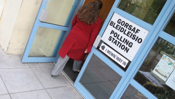 Person yn cerdded mewn i gorsaf pleidleisio